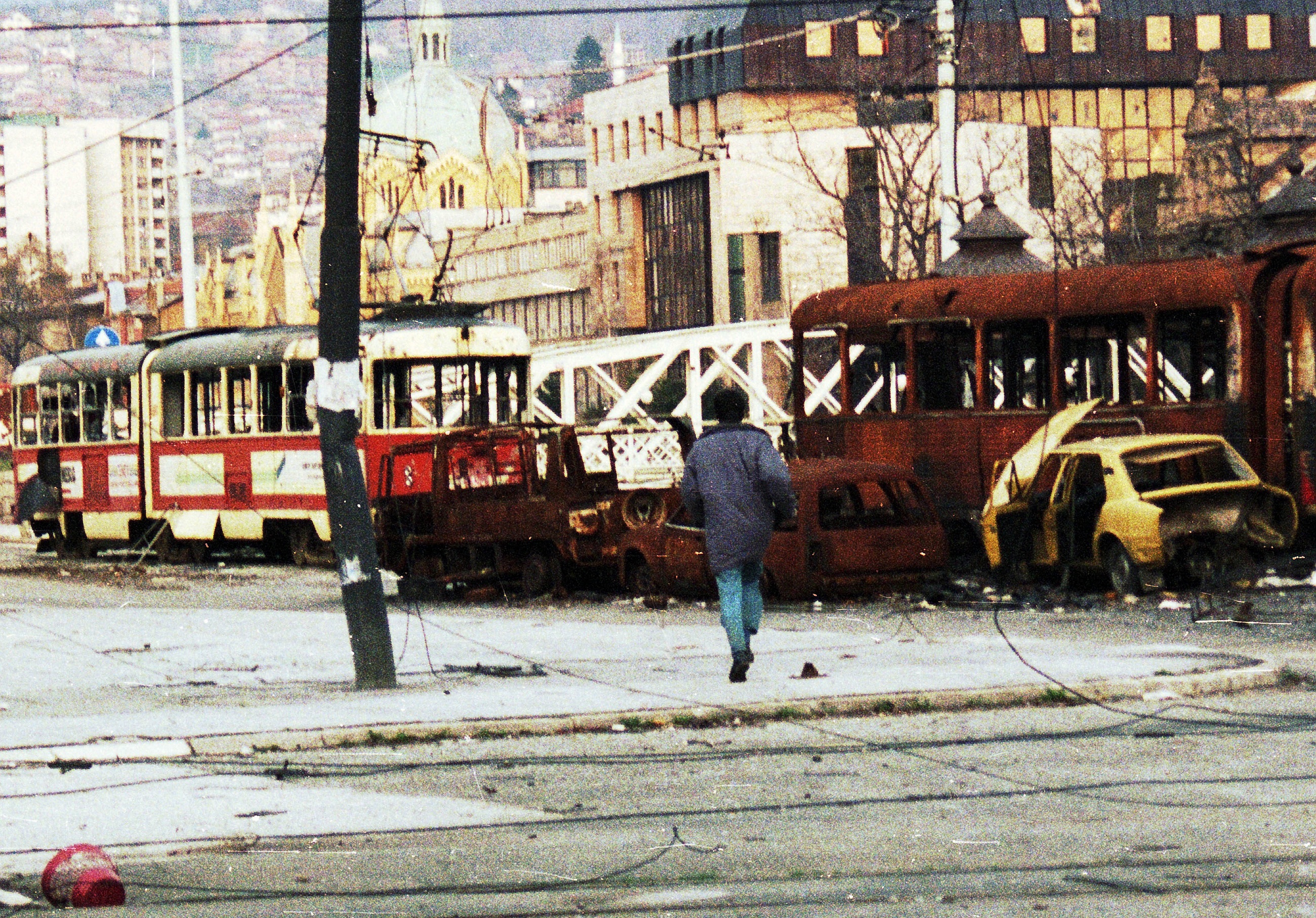Foto: Shutterstock, Fotonorth Muž se odvážně vydává přes palbu odstřelovačů, aby proběhl mezi zničenými tramvajemi a auty v Sarajevu v Bosně, v neděli 4. dubna 1993.